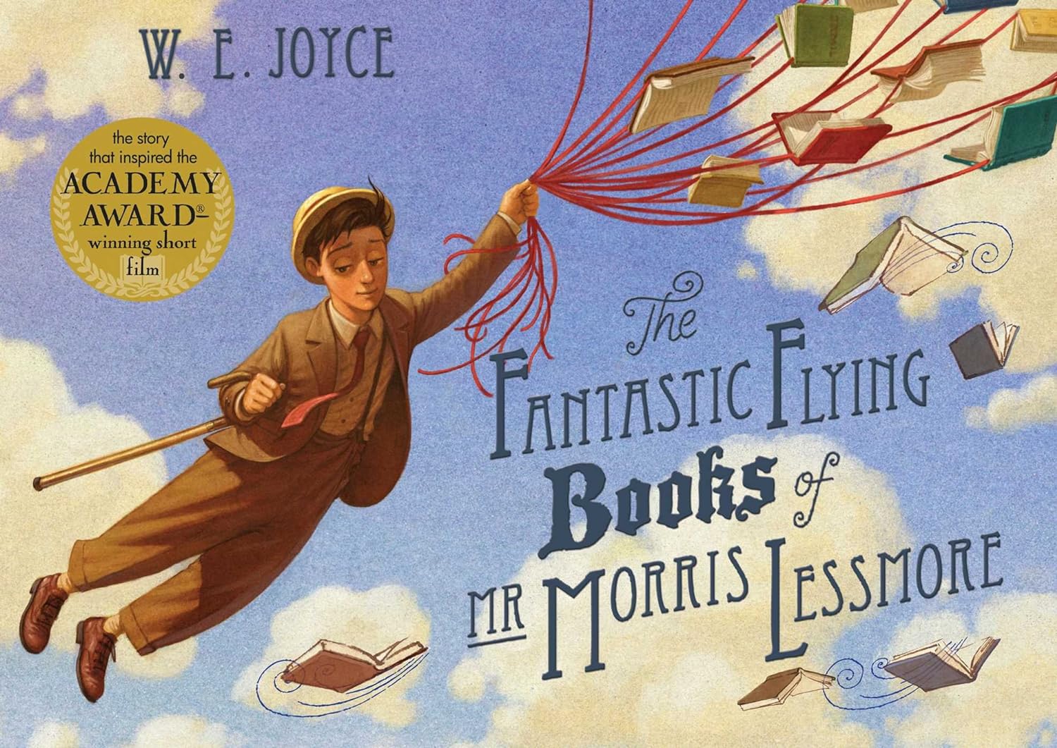Book cover of The Fantastic Flying Books of MR Morris Lessmore. A boy, dressed in a suit and tie with a hat and cane, flying through the sky holding onto a cluster of red strings attached to flying books. 